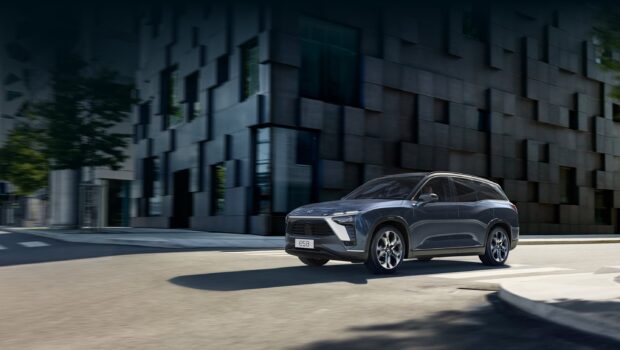 A blue Nio Auto is driving on a city street near modern buildings, 2K Desktop Wallpaper