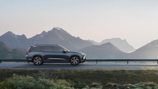 A Nio Auto drives along a scenic mountain road with a clear sky in the background, 2K Desktop Wallpaper
