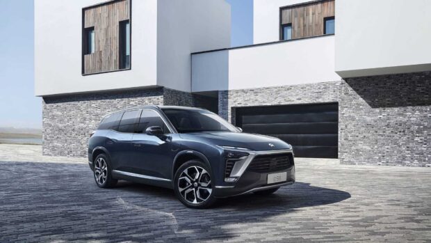 A sleek Nio Auto is parked outside a contemporary house, HD Desktop Wallpaper