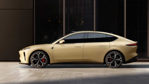 A beige Nio Auto car is parked in front of a dark modern building reflecting in the windows, HD Desktop Wallpaper