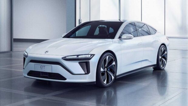 A sleek white Nio Auto electric sedan is showcased in a modern showroom setting, highlighting its design and features, HD Desktop Wallpaper