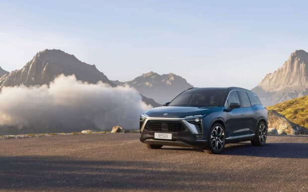 A Nio Auto vehicle ES8 is parked on a road with mountains in the background, 2K Desktop Wallpaper