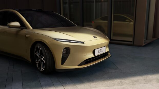 A gold Nio ET5 electric car is parked near modern glass buildings, 4K Desktop Wallpaper