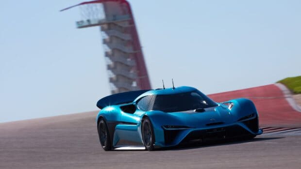 A blue Nio electric sports car speeds past a curved section of the race track, 4K Desktop Wallpaper