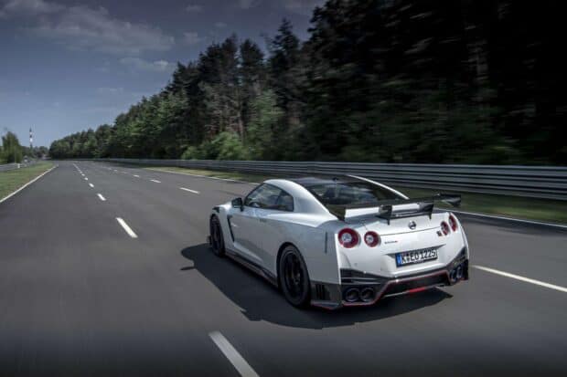 A white Nissan GT R is driving fast on a race track surrounded by trees, HD Desktop Wallpaper