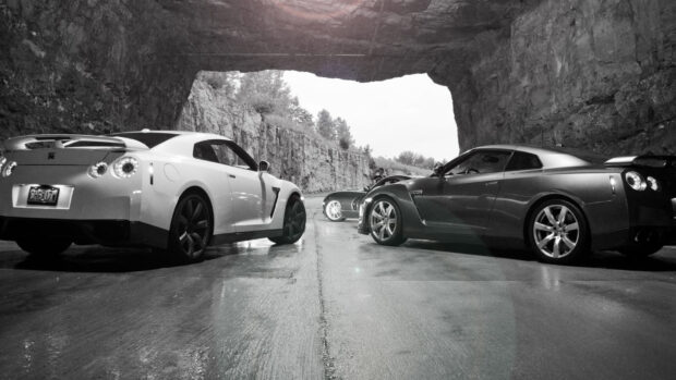 Two Nissan GT R cars parked inside a rocky tunnel, HD Desktop Wallpaper