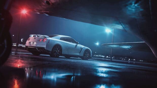 A Nissan GT R is parked under streetlights reflecting on wet pavement at night, 4K Desktop Wallpaper