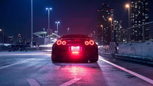 A Nissan GT R is parked on a city street with illuminated tail lights at night, 4K Desktop Wallpaper