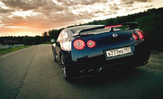 A black Nissan GT R is parked on an empty road during sunset with glowing rear lights, HD Desktop Wallpaper