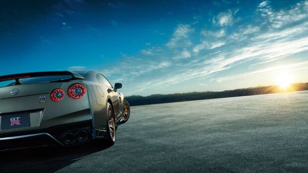 A Nissan GT R is parked on an open road with the sun setting behind mountains, HD Desktop Wallpaper