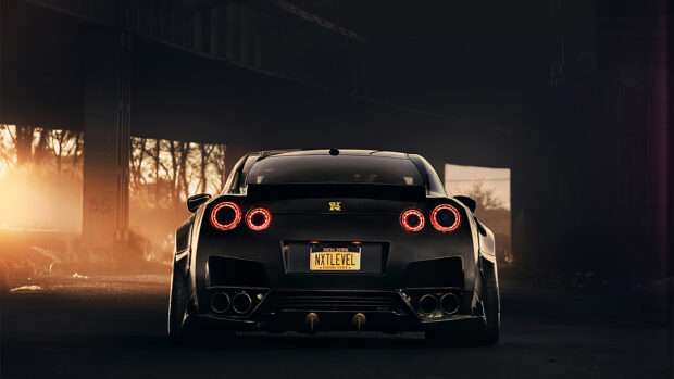 The Nissan GT R is parked under a bridge with glowing tail lights during sunset, 2K Desktop Wallpaper