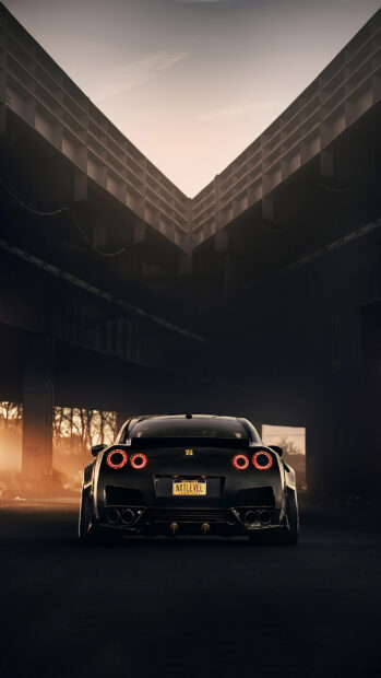 A Nissan GT R car is parked under a bridge with glowing taillights at sunset, 4K Phone Wallpaper