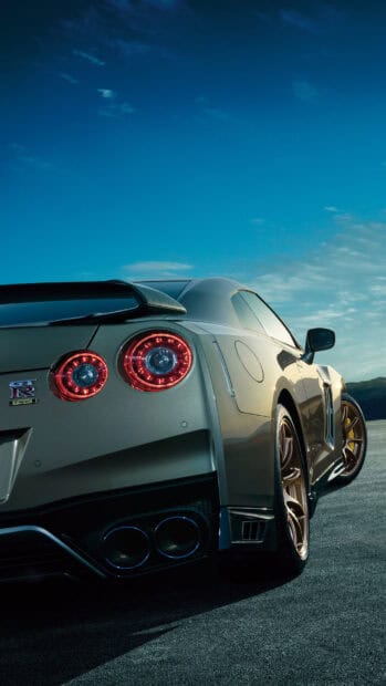 A Nissan GT R with red tail lights is parked on an empty road at sunset, 4K Phone Wallpaper