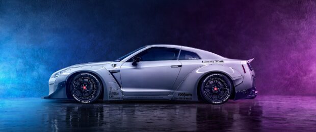 A silver Nissan GT R stands against a neon blue and purple wall with reflections on the floor, 2K Desktop Wallpaper