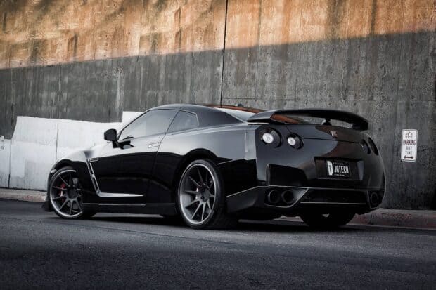 A black Nissan GT R is parked near a concrete wall with a parking sign, HD Desktop Wallpaper