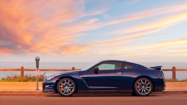 A blue Nissan GT R is parked by the ocean with a scenic sunset sky, HD Desktop Wallpaper
