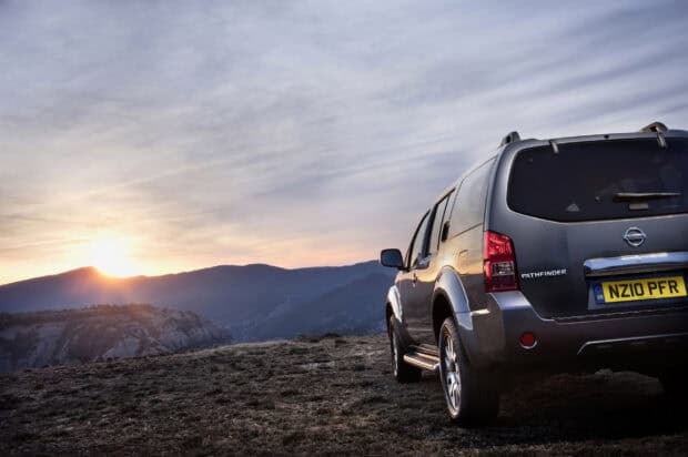 A Nissan Pathfinder is parked on a hill with a sunset over mountain ridges, 2K Desktop Wallpaper