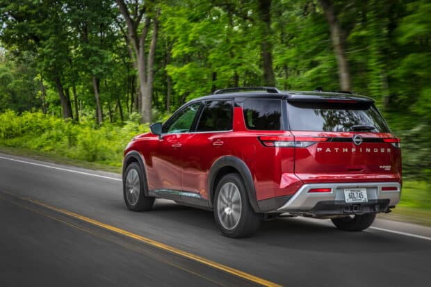 A red Nissan Pathfinder is driving down a tree lined road under natural daylight, HD Desktop Wallpaper