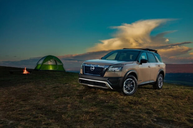 A Nissan Pathfinder is parked near a green tent with a campfire under a dramatic sky, 2K Desktop Wallpaper