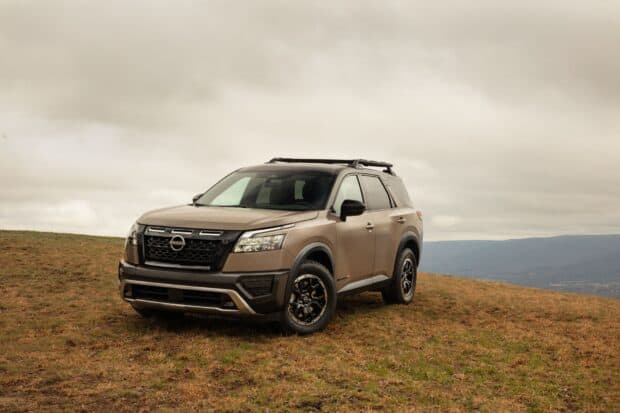 A Nissan Pathfinder is parked on a grassy hill under a cloudy sky, HD Desktop Wallpaper