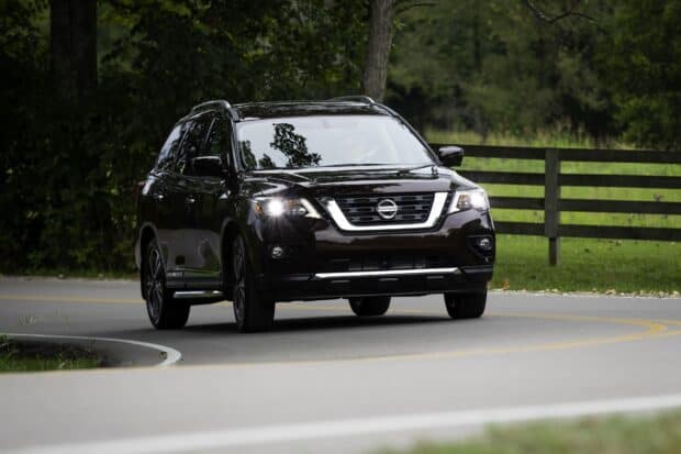 A black Nissan Pathfinder drives along a winding road surrounded by trees and greenery, HD Desktop Wallpaper