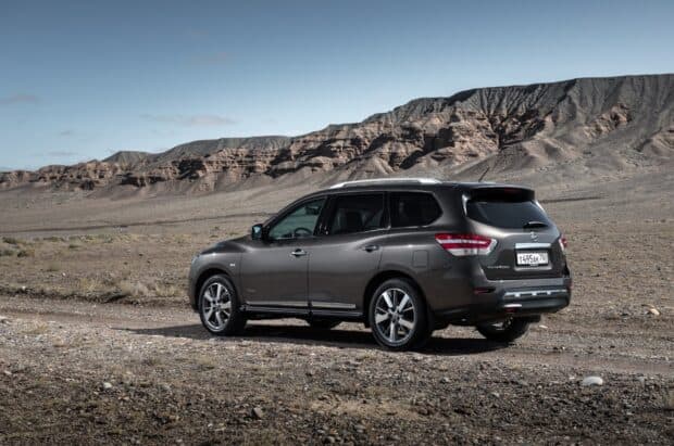 A Nissan Pathfinder is parked on a dirt road in a rocky desert area with mountains in the background, HD Desktop Wallpaper