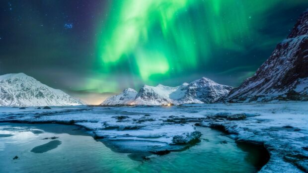 The Norway Wallpapers shows the northern lights glowing over snow covered mountains and frozen water, HD Desktop Wallpaper