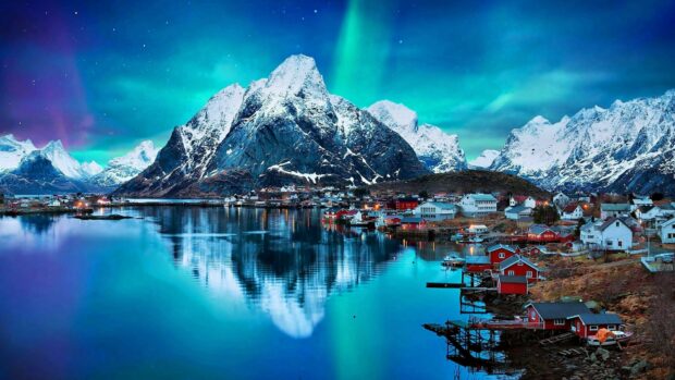The northern lights shine brightly above snowy mountains and a small village in Norway, 4K Desktop Wallpaper