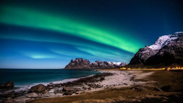 Northern lights glow above snowy mountains by the ocean in Norway at night, 4K Desktop Wallpaper