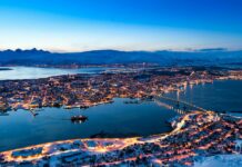 A scenic view of Norway city lights glowing at twilight over snowy landscape and water, 4K Desktop Wallpaper