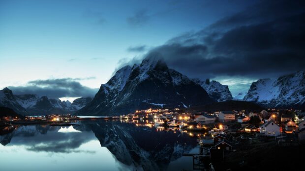 A peaceful Norway village is illuminated at night beneath towering mountains, 4K Desktop Wallpaper