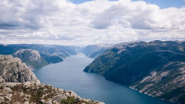 A breathtaking view of Norwegian fjords stretching between mountains under a cloudy sky, 4K Desktop Wallpaper