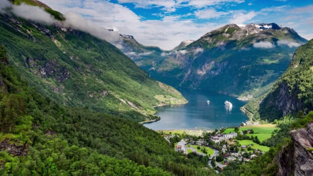 A stunning view of Norwegian fjords surrounding a peaceful village under cloudy skies, HD Desktop Wallpaper