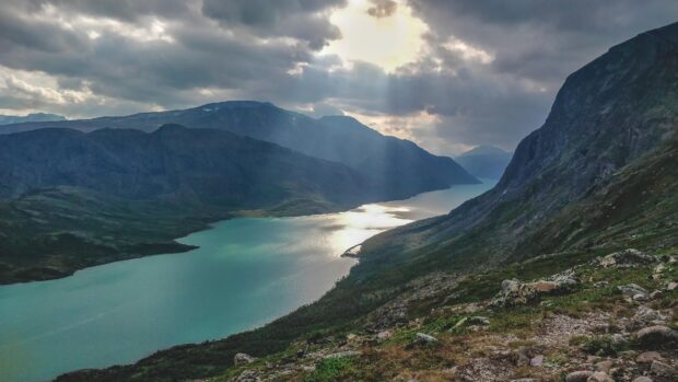 The Norwegian fjords are lit by sunlight breaking through clouds over the mountains, 4K Desktop Wallpaper