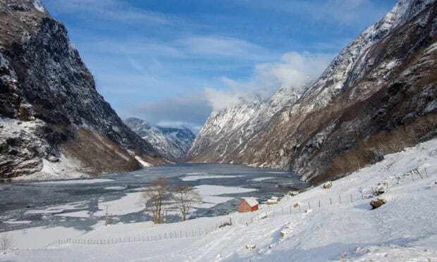 A snowy landscape of Norwegian fjords with icy water and mountains under a clear sky, HD Desktop Wallpaper