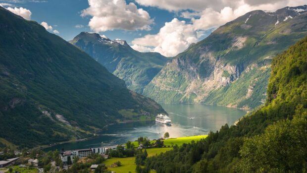 A cruise boat sails through the Norwegian fjords surrounded by green mountains and blue sky, HD Desktop Wallpaper