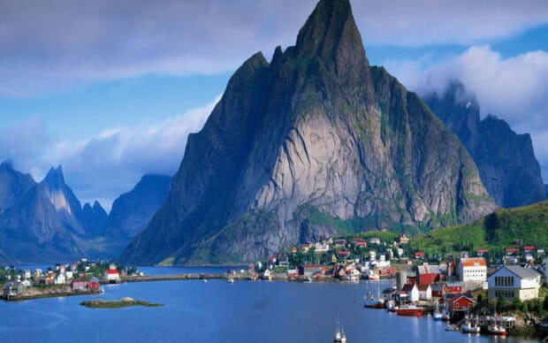 A beautiful Norwegian fjords village with mountains and boats under a cloudy sky, 2K Desktop Wallpaper