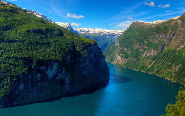 A stunning scene of Norwegian fjords with clear blue water and snow capped mountains, 2K Desktop Wallpaper