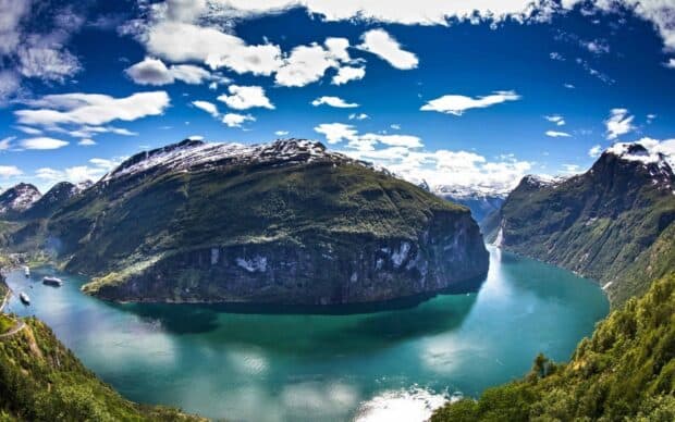 A stunning view of Norwegian fjords with mountains and blue water under a bright sky, 2K Desktop Wallpaper