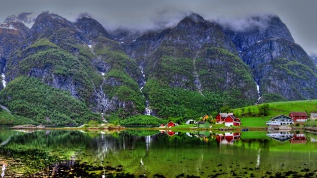 A serene view of Norwegian fjords with green mountains and traditional houses, 2K Desktop Wallpaper