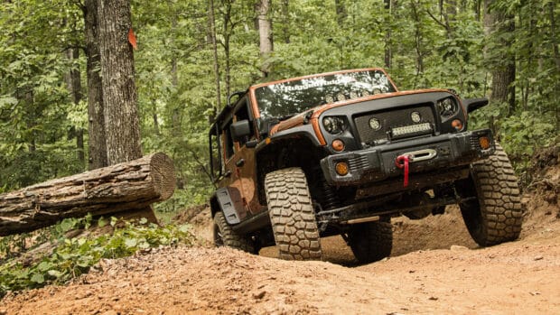 A rugged off road vehicle navigating a forest trail with rough terrain, HD Desktop Wallpaper