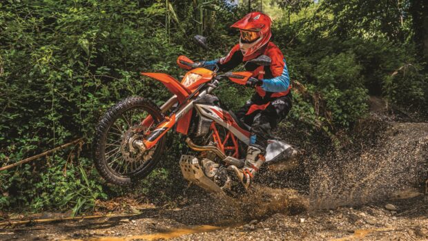 A rider on an Enduro motorbike splashes mud while riding through a forest trail, 4K Desktop Wallpaper