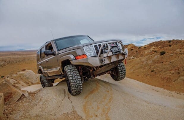 A Jeep Commander is climbing a rocky hill in a desert terrain, HD Desktop Wallpaper