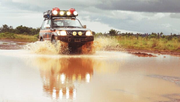 An off road vehicle splashes through muddy water on a rough path, HD Desktop Wallpaper