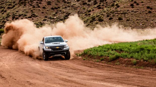 A white Chevrolet truck creates dust clouds while off road driving on a winding dirt trail, 4K Desktop Wallpaper
