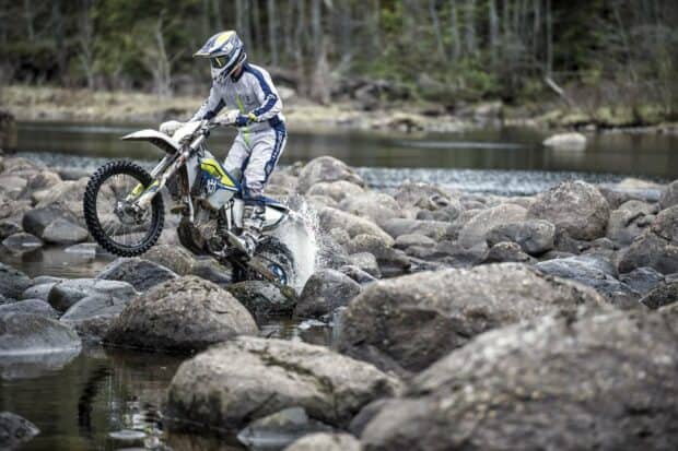 A rider on an enduro motorbike crosses rocky water terrain, HD Desktop Wallpaper