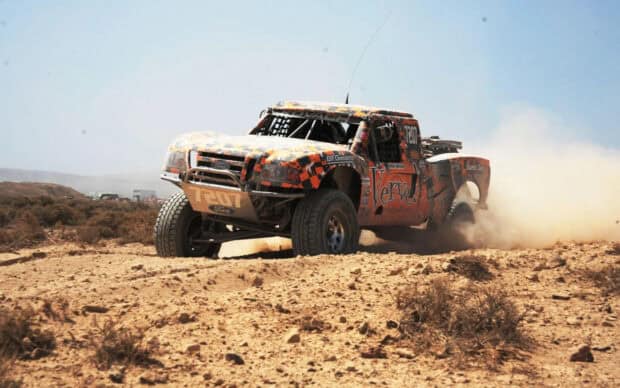 A racing truck driving off road through a dusty desert landscape, 2K Desktop Wallpaper