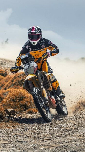 A rider is speeding on a rough dirt trail on an enduro motorbike, kicking up dust and stones, HD Mobile Wallpaper