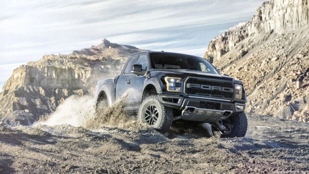 A black truck is driving off road on a dusty rocky landscape with mountains in the background, 4K Desktop Wallpaper