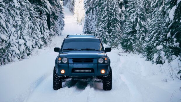 A rugged off road vehicle navigates a snow covered path through a dense forest, HD Desktop Wallpaper